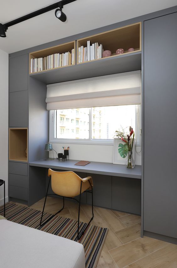 a minimalist home office nook with a built-in storage unit, a window for a view, a small yellow chair is all you need for work