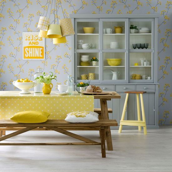 a pretty and cute grey and yellow dining room with floral wallpaper, a grey buffet, a wooden dining set, pendant lamps and yellow textiles