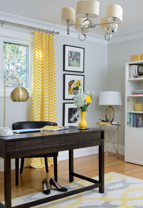 a refined mid-century modern home office with light grey walls, a dark desk and a dark chair, a brass lamp and a grey and yellow printed rug