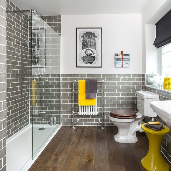 a retro bathroom with white walls and grey subway tiles, with white appliances, yellow touches and black shades