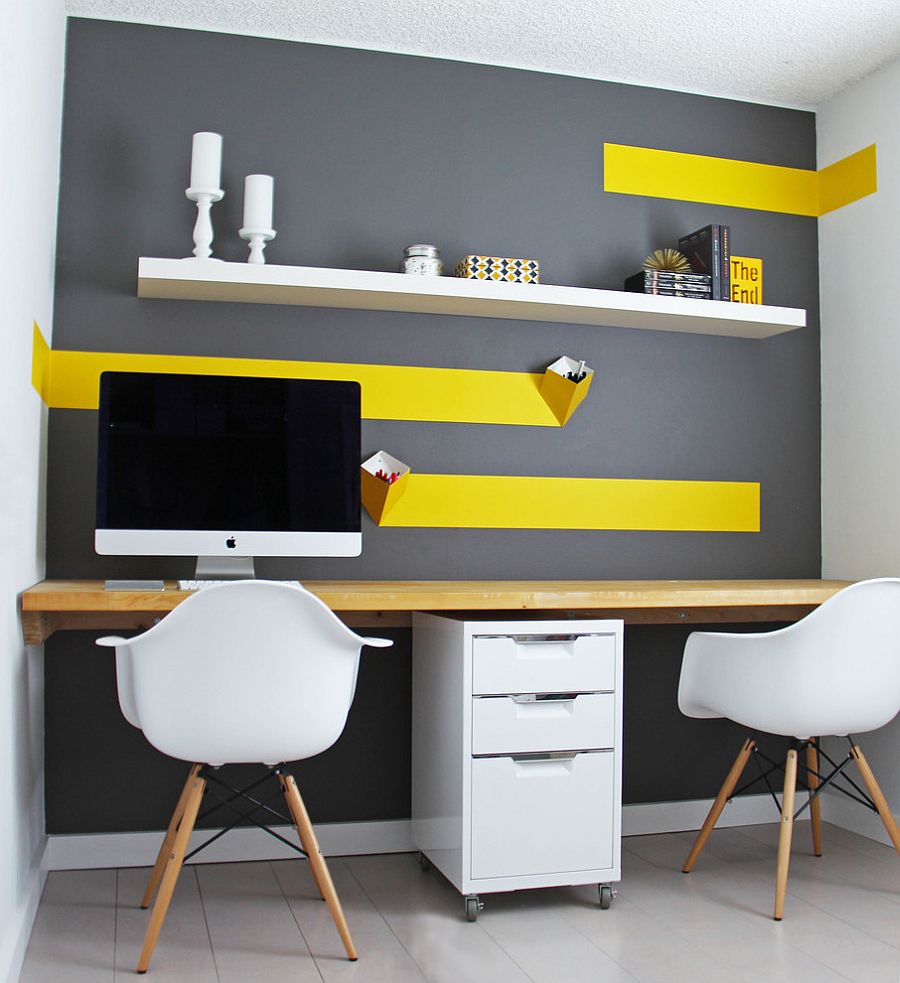 a small contemporary home office with a grey accent wall with bold yellow touches and an open shelf, a shared desk and a couple of chairs