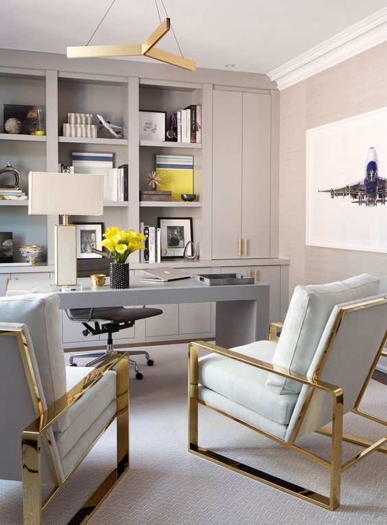 a sophisticated home office in dove grey, with built in storage units, a sleek grey desk and gold and grey chairs plus yellow touches