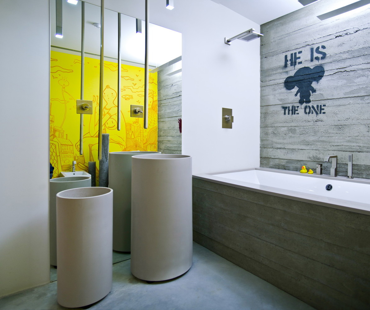 A super contemporary bathroom with rough concrete walls and a tub clad with it, catchy free standing sinks, ceiling lamps and a yellow statement wall