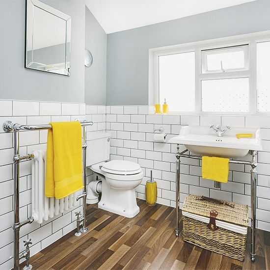 a vintage bathroom with grey walls and white subway tiles, vintage fixtures, mirrors and yellow accessories and touches