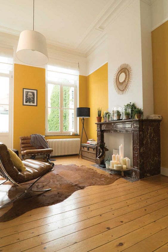 an elegant living room with yellow walls, a fireplace with candles, leather chairs and potted plants on the mantel