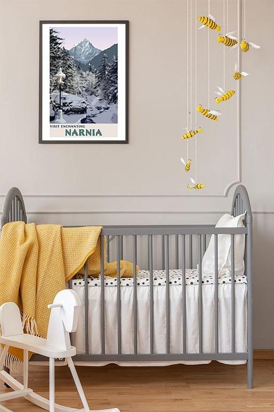 an ethereal nursery with dove grey paneled walls, a vintage grey crib, a bee mobile and some yellow textiles