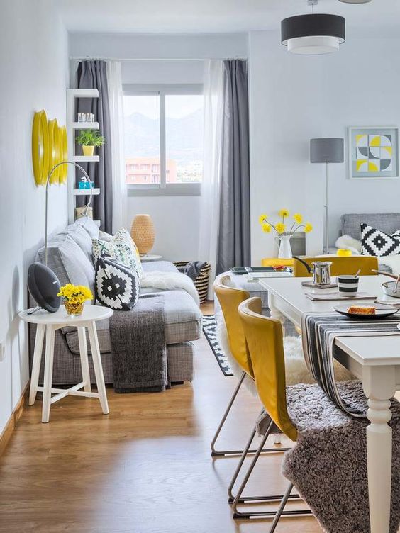an open layout with a dining and a living room, done in grey, white and accented with sunny yellow is a cool and bold idea