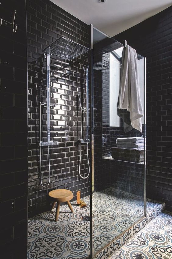 02 a chic black bathroom with glossy tiles and patterned ones on the floor, a glass shower space is refined