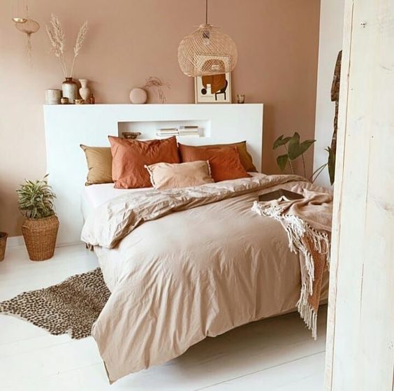 03 a contemporary boho earthy bedroom with a terracotta wall, earthy tone bedding, vases, artworks and a pendant lamp