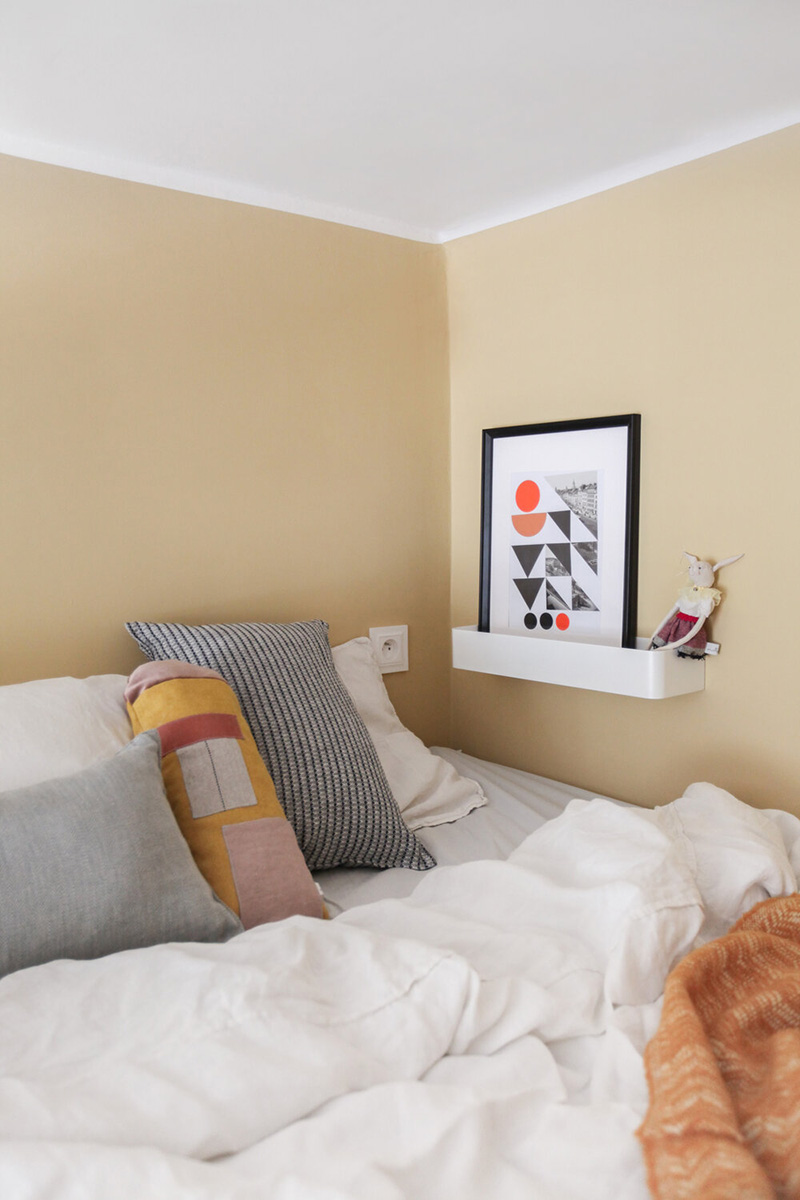A socket and a ledge with an artwork make the sleeping space practical and functional