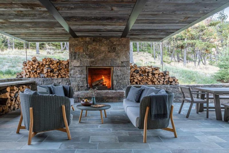 04 The patio shows off a stone clad fireplace, some wicker furniture, lots of firewood