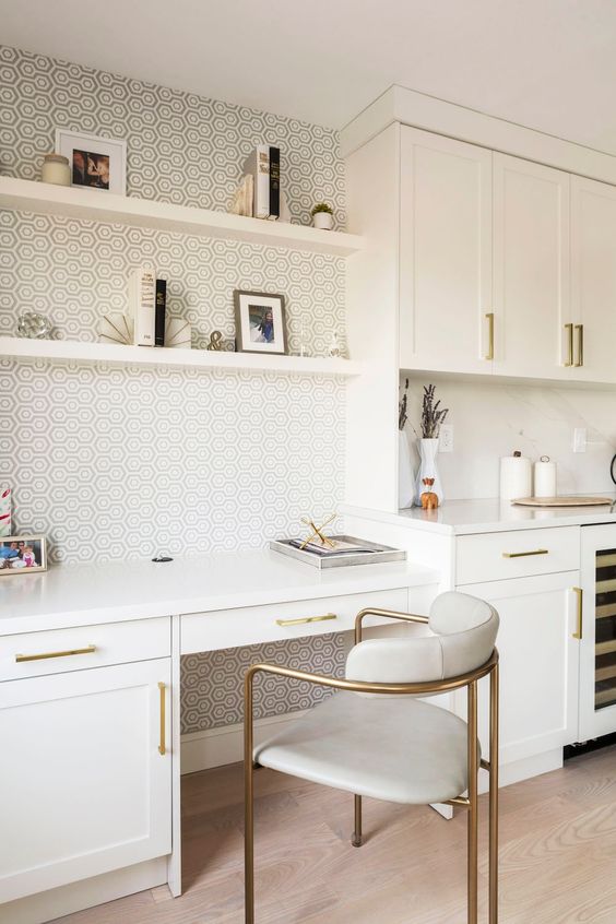 an elegant and refined white kitchen with a home office, with brass touches and a stylish wallpaper wall