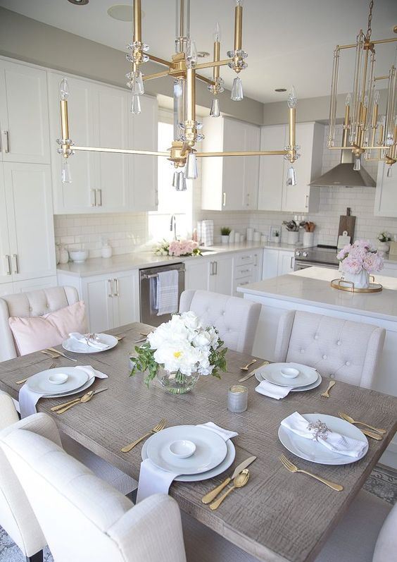A neutral and very elegant eat in kitchen with stylish cabinetry, gold and crystal chandeliers and neutral furniture