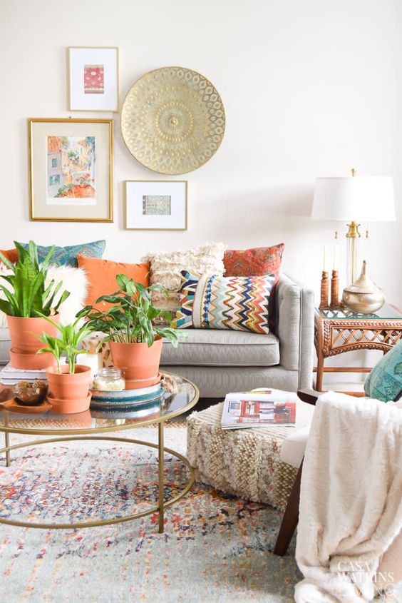 a pretty and airy global style living room with colorful pillows, potted plants, a mini gallery wall with art