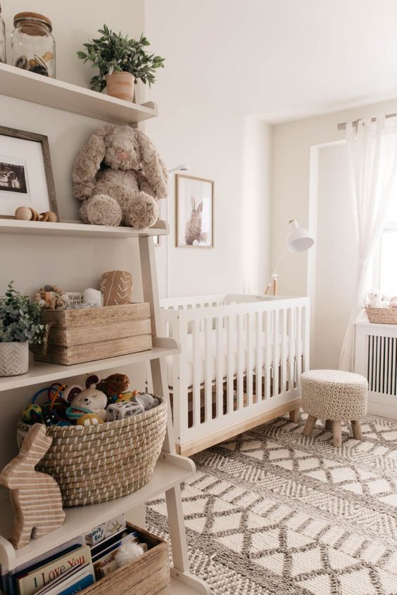 A warm colored gender neutral nursery with light furniture, an open shelf and a printed rug is very cozy