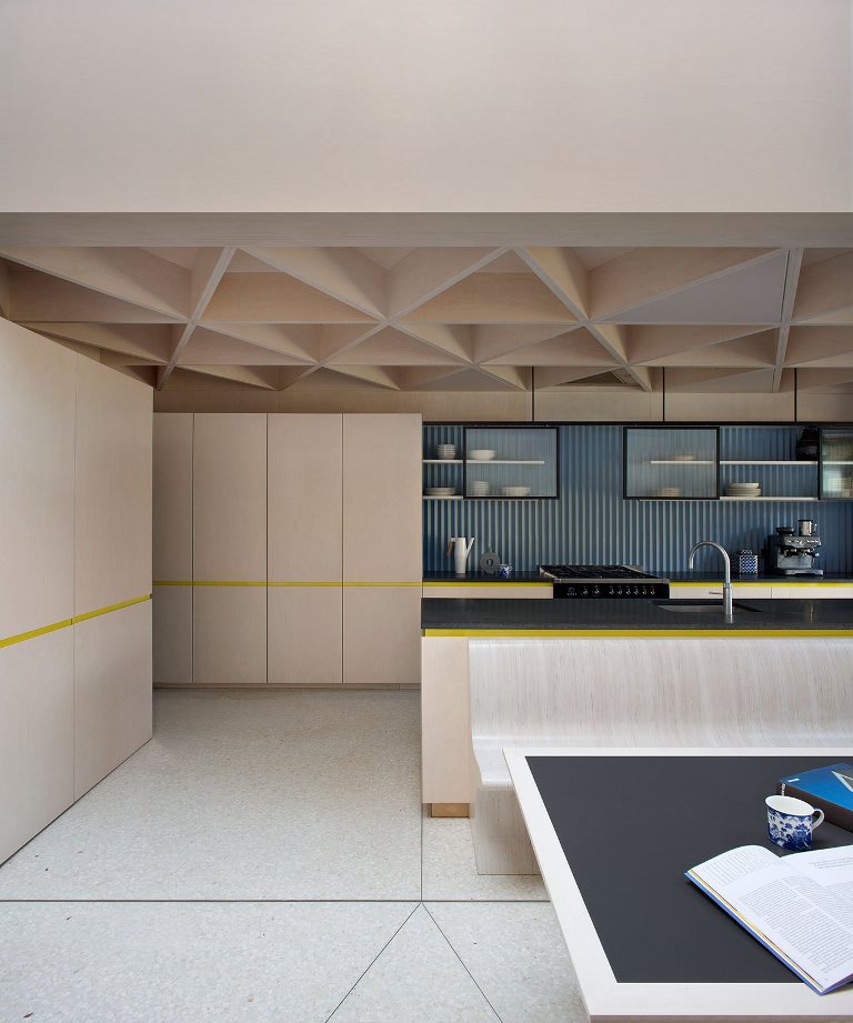 06 The kitche features a geometric ceiling, a blue corrugated steel backsplash and a black stone countertop