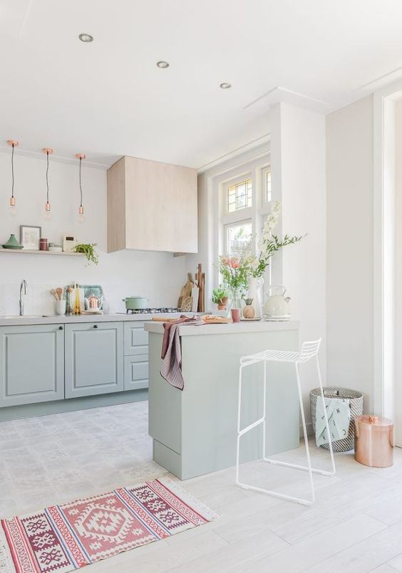 a beautiful pastel kitchen with mint green cabinets, touches of pink, copper and a geometric rug shows off a cool color combo