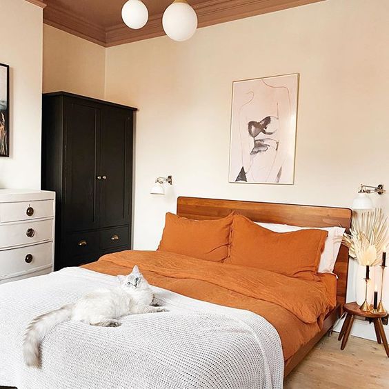 06 a chic modern bedroom with black and white furniture, a rich stained bed, orange bedding, leaves and grasses
