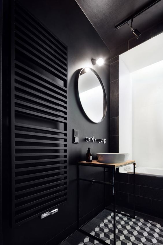 a minimalist black bathroom with matte walls and a radiator, a geometric tile floor and an airy vanity