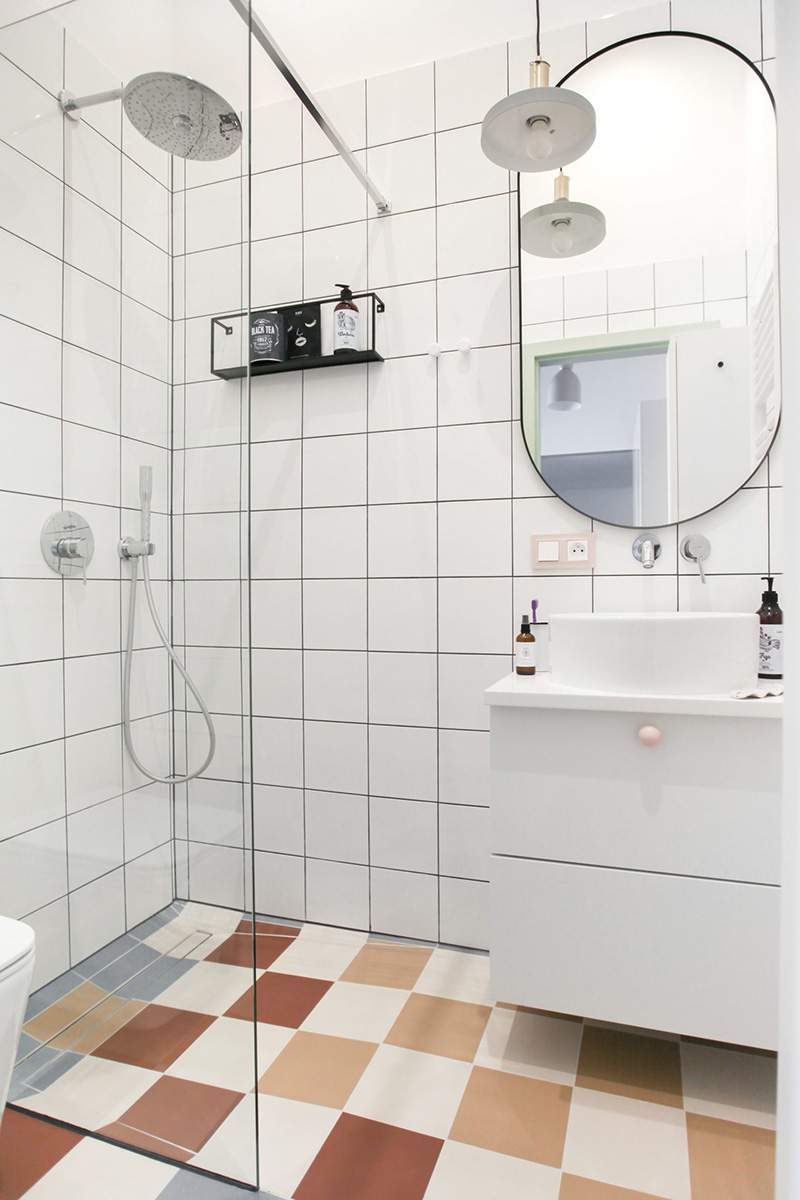 The bathroom is clad with white square tiles and colorful ones on the floor, and there's everything necessary here