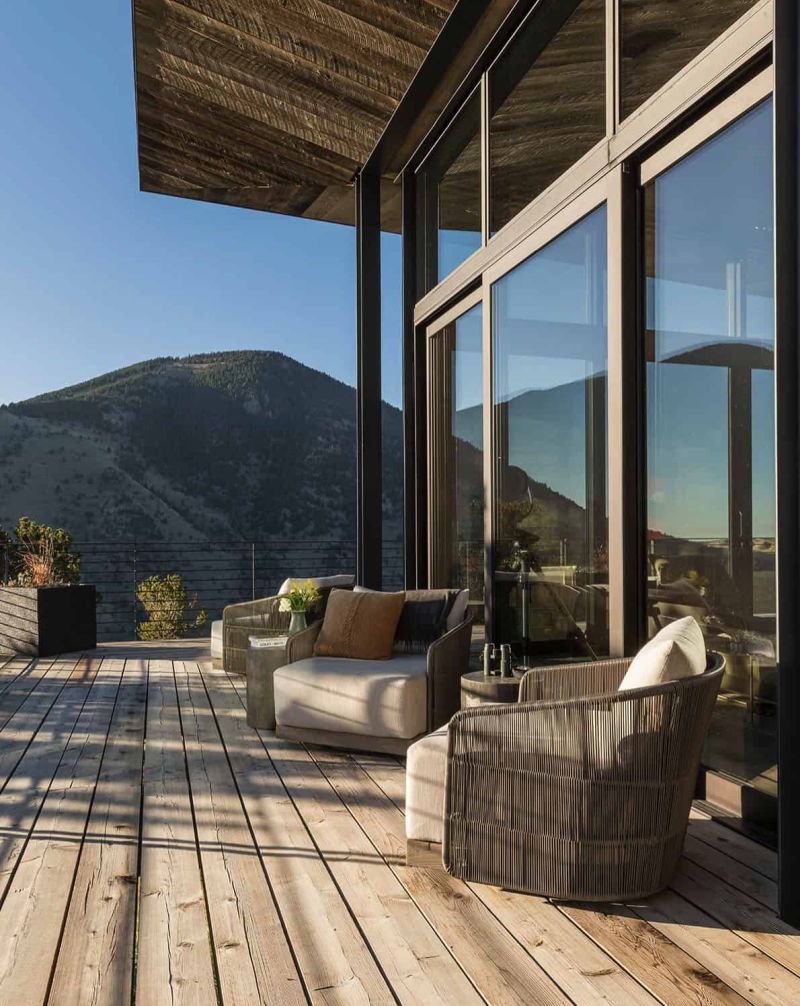 The sun filled wooden deck is exposed to the rugged landscape around it