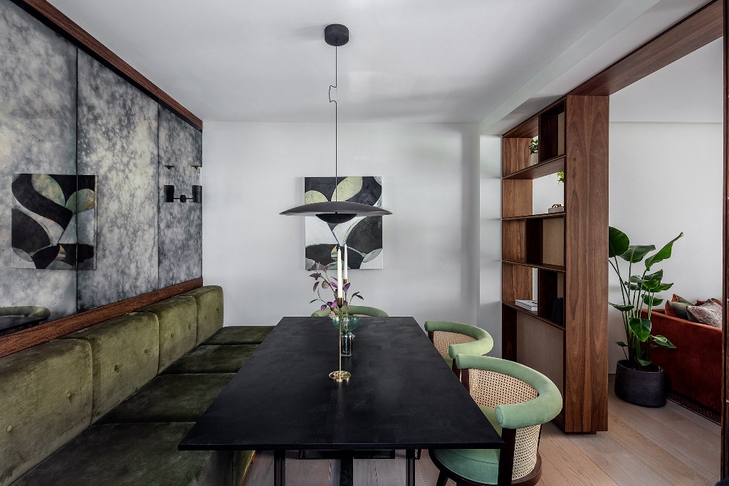 The dining space shows off a banquette seating, a black stone table and some catchy green chairs