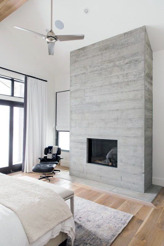 09 a modern bedroom in neutrals, with much natural light and a concrete fireplace that gives the space a cool look
