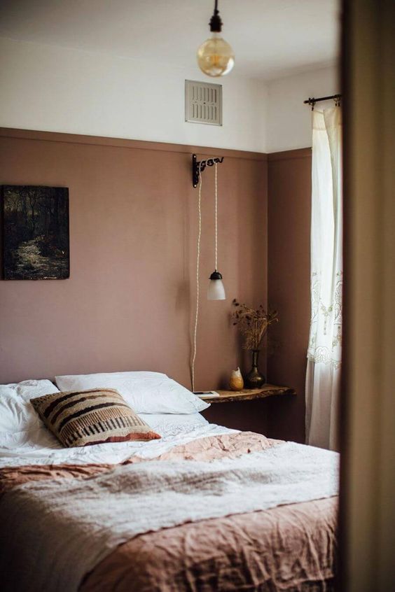 09 an earthy toned bedroom with a mauve statement wall, floating nightstands, terracotta bedding and simple lamps