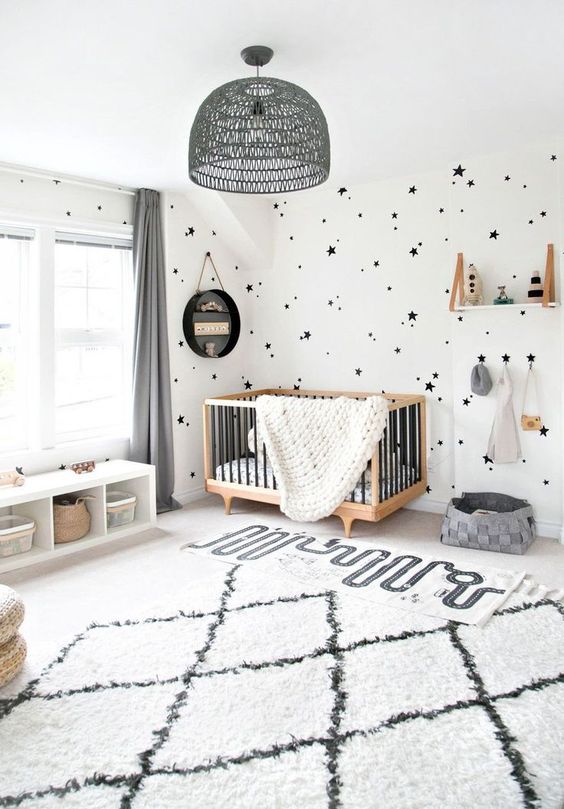 a chic monochromatic nursery in black and white, with a cool modern crib, a shelf and printed textiles