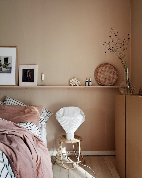10 a welcoming and soft earthy toned bedroom with tan walls, pink and striped bedding, artworks and grasses