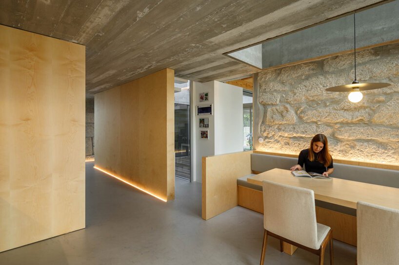 The dining space is all minimal, with built-in benches and a table and a stone lit up wall