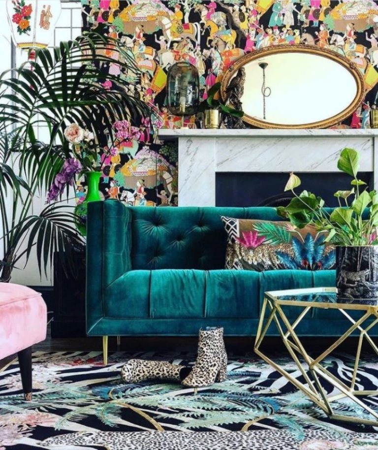 a luxurious maximalist living room with colorful wallpaper, bright rugs and pillows, potted plants and gold touches