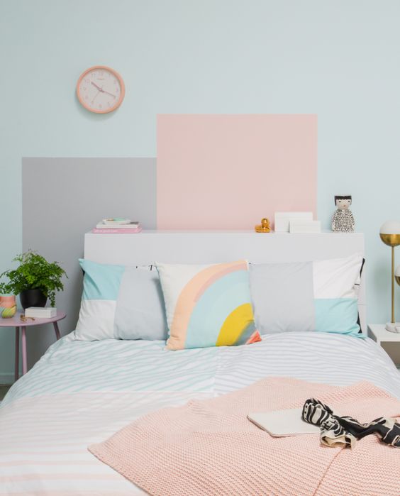 a pastel bedroom with a light blue wall and color blocking, pastel and color block bedding and a pink clock