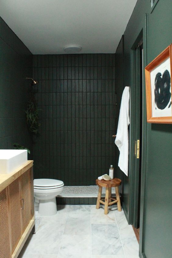 16 a refined and moody dark green and black bathroom with a white marble tile floor and a wooden vanity