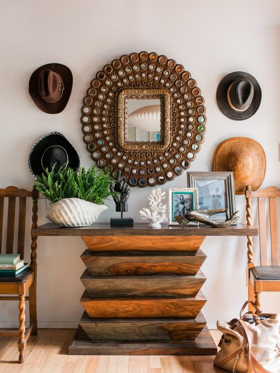 a catchy entryway with a wooden geometric console table, cowboy hats, potted greenery, driftwood and corals
