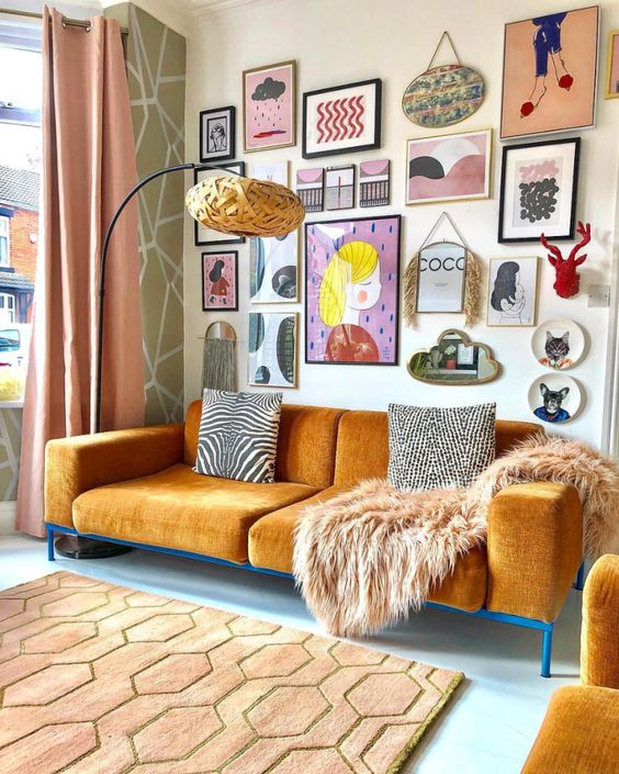 A warm toned maximalist living room with ocher furniture and a bold and creative gallery wall with various art