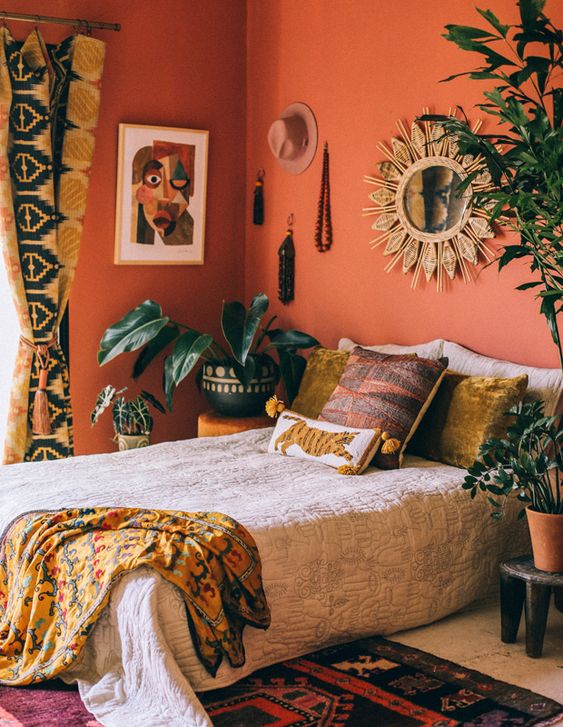 a colorful global style bedroom with red wlals, bright bedding, potted greenery and statement plants and printed textiles