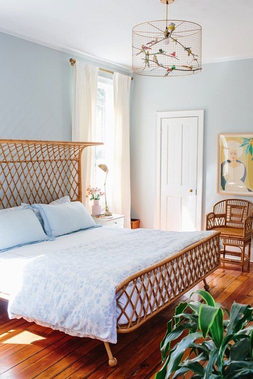 a light blue bedroom, rattan furniture, a catchy chandelier with birds, artworks and potted plants