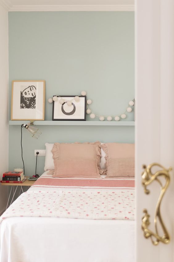 20 a light blue bedroom with a ledge, pink and white bedding, a garland and simple artworks is welcoming