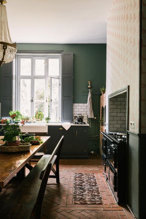 a vintage hunter green kitchen with a large vintage cooker, white countertops and black shutters and a dining space