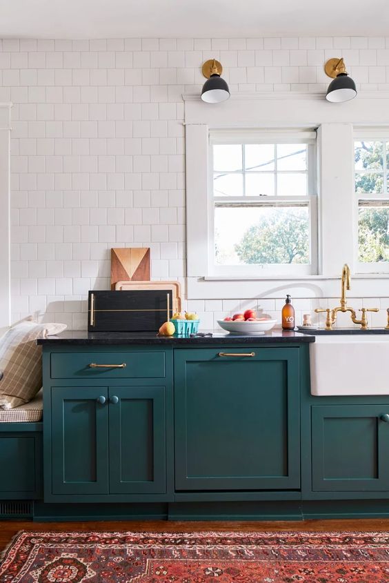 a stylish mid-century modern teal kitchen with black countertops, a white tile wall and touches of gold here and there