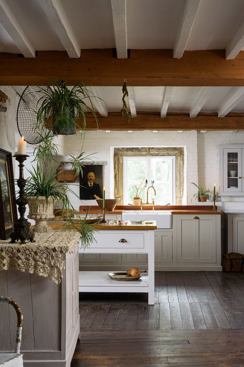 23 a beautiful old world kitchen with wooden beams, elegant neutral cabinets, potted greenery and candles in candleholders