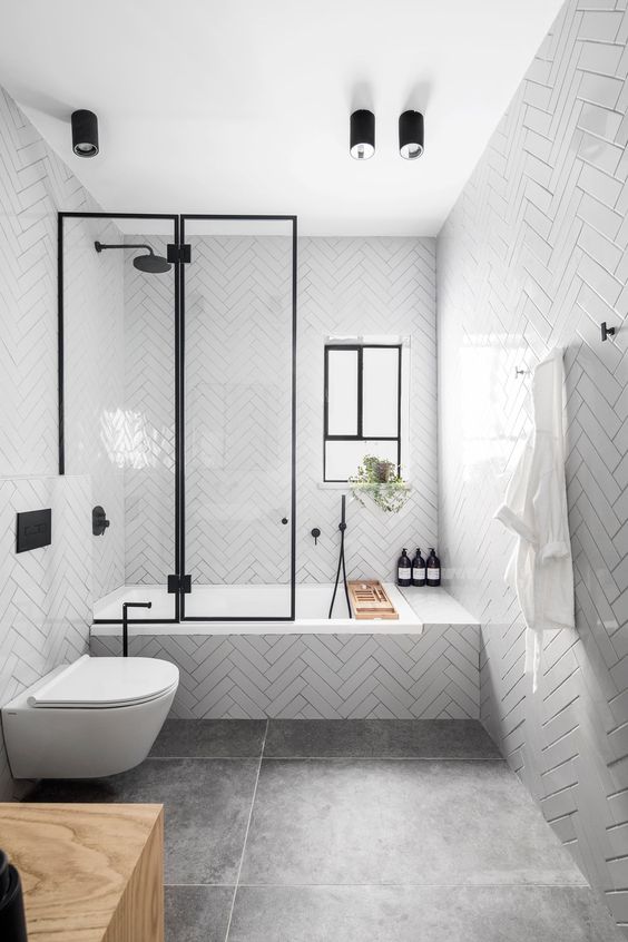 24 a contemporary bathroom with glossy white tiles, large scale tiles on the floor, black fixtures and a window for more light