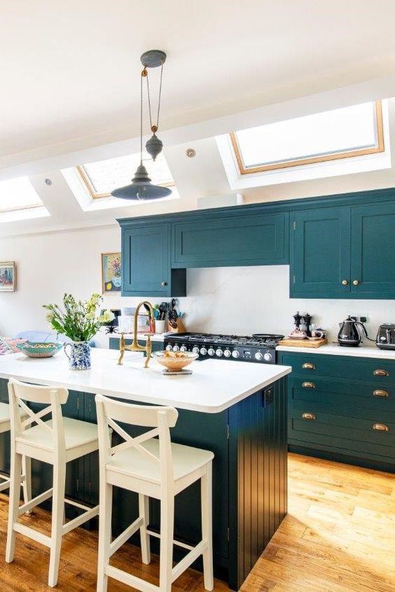 a lovely teal kitchen with a white backsplash and countertops, a matching kitchen island with white countertops and a backsplash