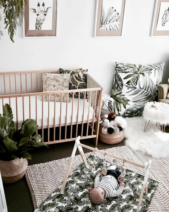 a neutral tropical nursery with light-stained wooden furniture, tropical print textiles and potted plants