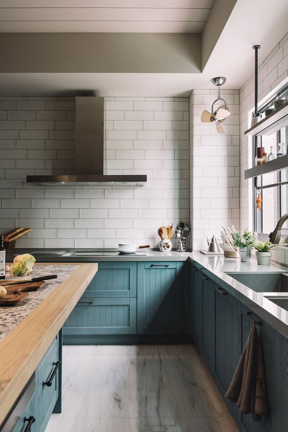 27 a catchy teal kitchen with vintage cabinets, a white tile backsplash, stone and butcherblock coutnertops and stainless steel fixtures