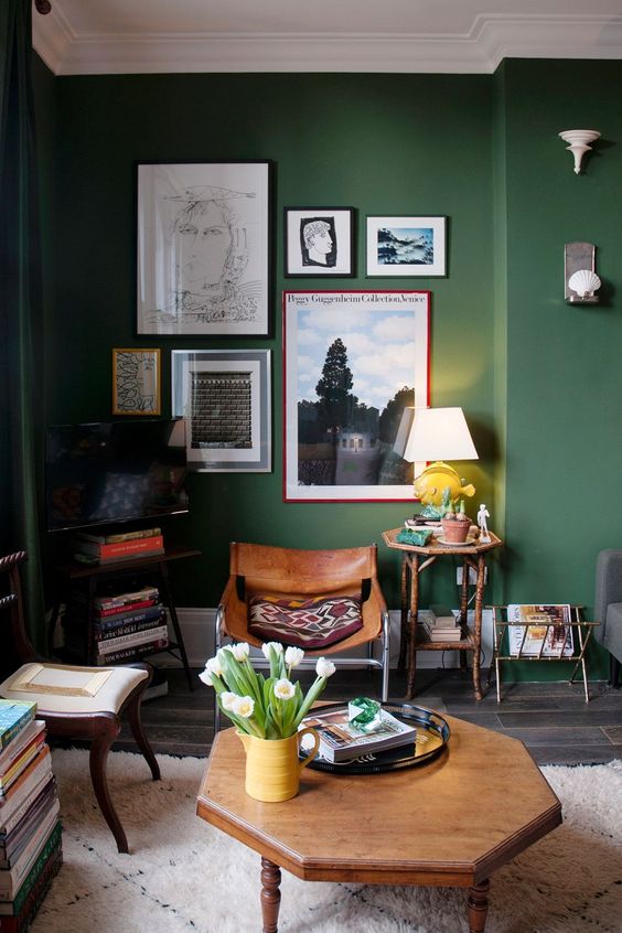 a stylish green living room with dark stained furniture, a gallery wall with bold art and printed pillows