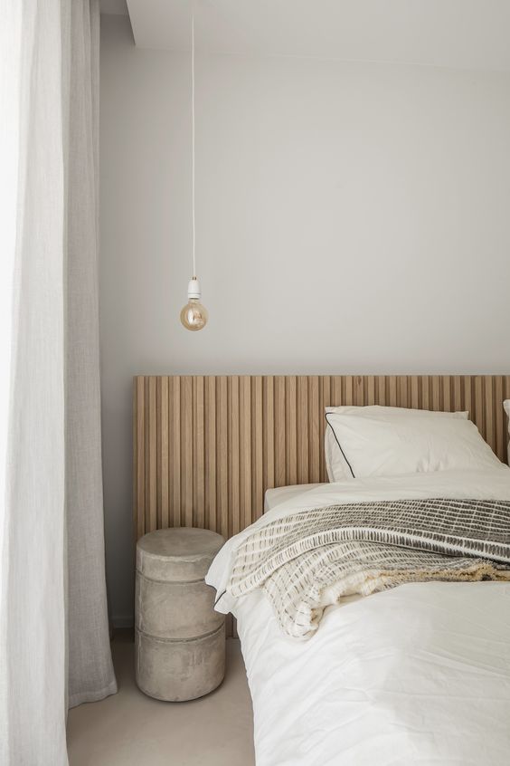 28 a chic bedroom with grey walls, a light stained bed, a concrete table and a pendant bulb