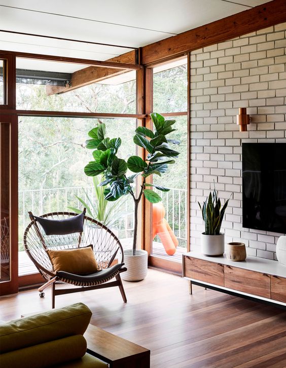 A neutral mid century modern living room with a brick wall, glazed walls and elegant furniture