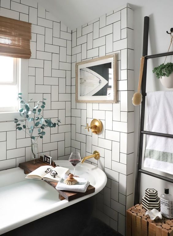 A chic neutral mid century modern bathroom with a black vintage tub, a contrasting artwork and shades